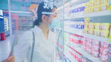 戴口罩的青年女人在超市挑选酸奶